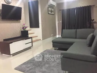 Modern living room with sleek gray sofa, wall-mounted TV, and elegant decor.
