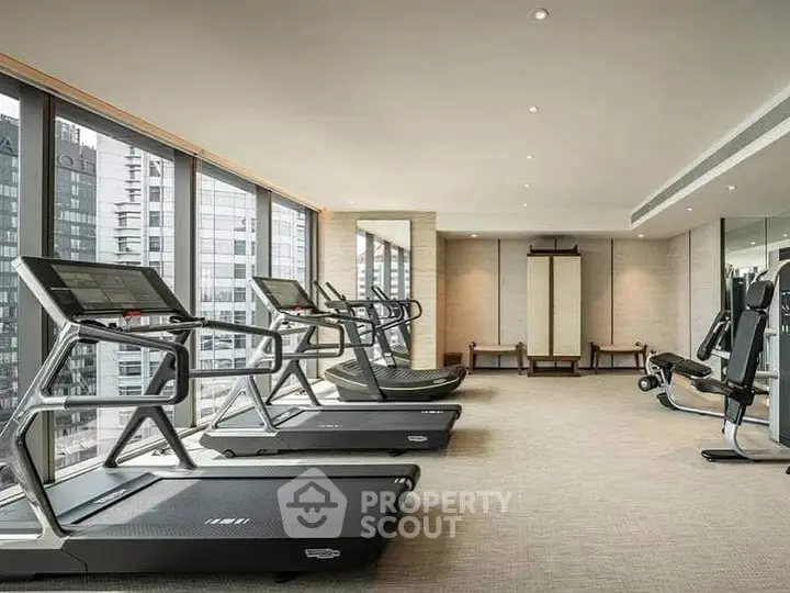 Luxurious gym with modern equipment and city view in high-rise building.