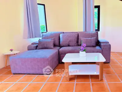 Charming living room with cozy purple sofa and modern coffee table on terracotta tiles.