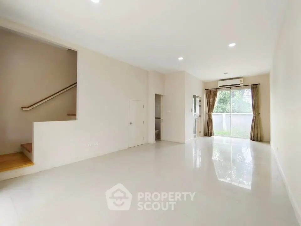 Spacious and bright living room with large window and staircase