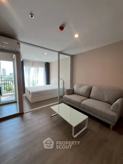 Modern apartment with cozy living room and bedroom, featuring a sleek sofa and glass coffee table.