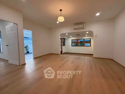 Spacious living room with wooden flooring and modern lighting in a bright home.