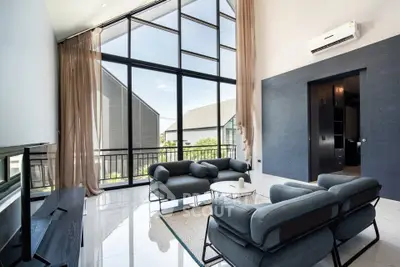 Luxurious modern living room with high ceilings and large windows offering stunning views.
