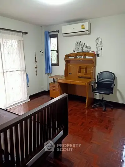 Cozy study room with wooden desk and chair, featuring natural light and air conditioning.
