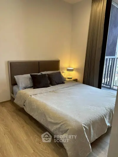 Cozy bedroom with modern decor and natural light from balcony view.