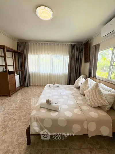 Spacious bedroom with large windows and elegant decor, perfect for relaxation.