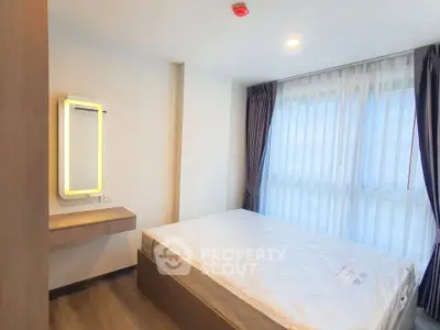 Modern bedroom with large window and stylish mirror in a contemporary apartment.