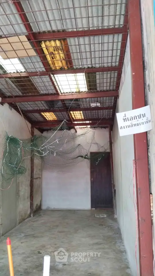Industrial-style unfinished room with metal roof and concrete walls, ideal for storage or workshop space.