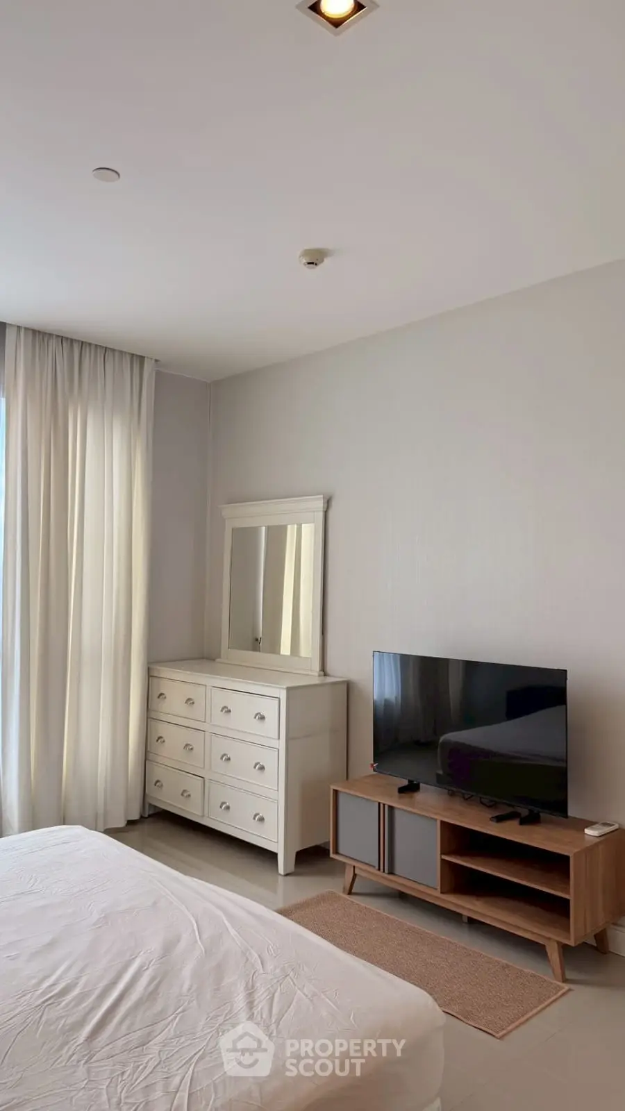 Spacious bedroom with modern furniture and natural light, perfect for a cozy living experience.
