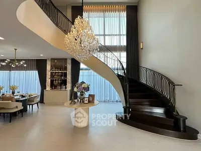 Luxurious living room with elegant staircase and chandelier, perfect for upscale living.