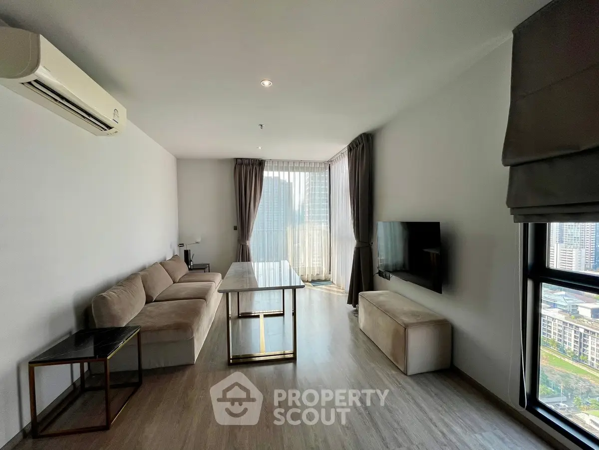 Modern living room with city view, featuring sleek furniture and large windows for natural light.