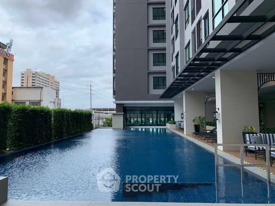 Luxurious modern apartment building with stunning outdoor pool and lush greenery.