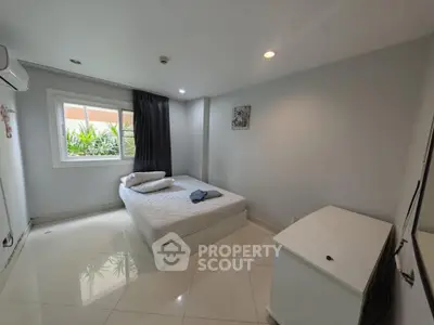 Modern minimalist bedroom with natural light and sleek white furnishings.