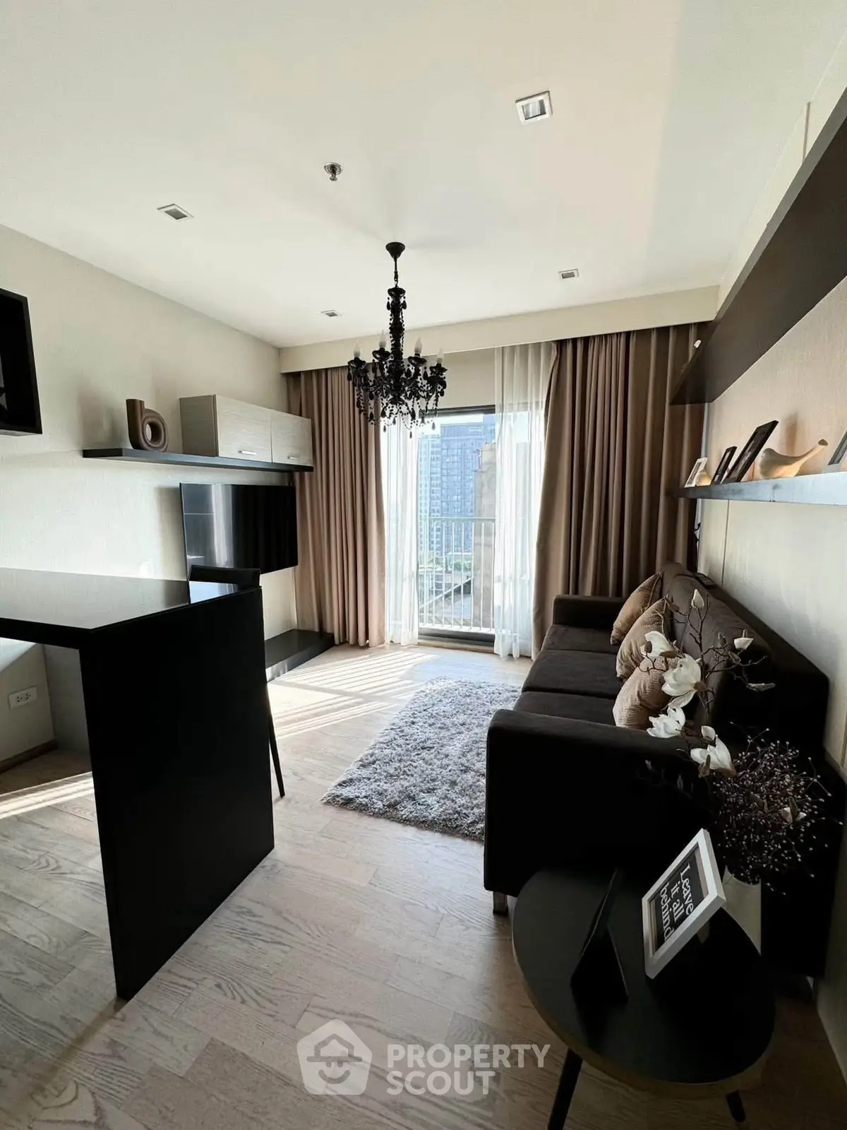 Modern living room with elegant chandelier and balcony view in a stylish apartment.