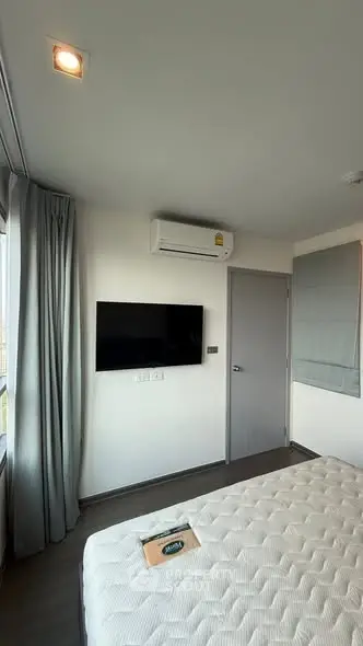 Modern bedroom with wall-mounted TV and air conditioning, featuring sleek design and natural light.