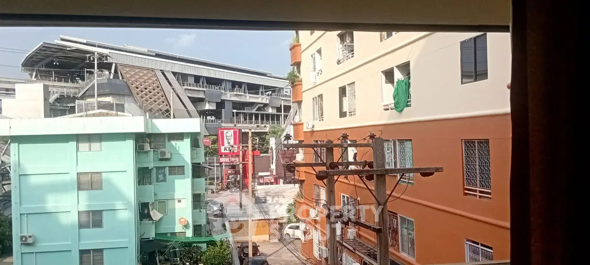 Urban view from window showcasing colorful buildings and city infrastructure.