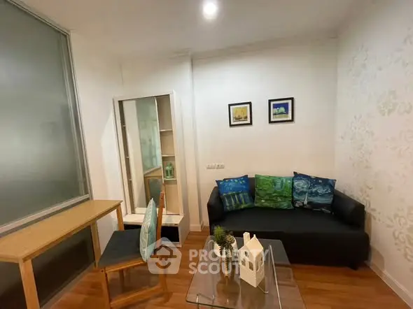 Cozy living room with modern decor and wooden flooring, featuring a comfortable sofa and stylish glass coffee table.