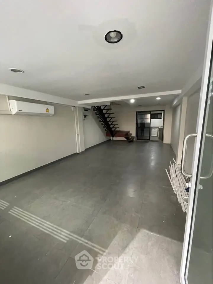 Spacious modern living room with sleek staircase and air conditioning, ideal for contemporary living.