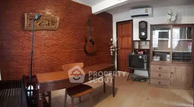 Charming vintage living room with brick accent wall, wooden furniture, and guitar decor.