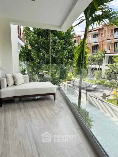 Luxurious balcony with glass railing and garden view in modern apartment complex.