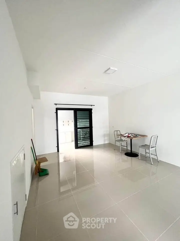 Spacious minimalist room with tiled floor and sliding glass door, ideal for versatile living space.
