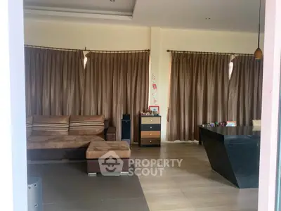 Spacious living room with modern furniture and elegant curtains, perfect for family gatherings.
