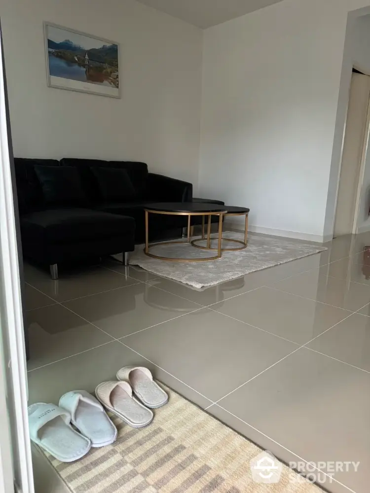 Modern living room with sleek black sofa and stylish coffee table on glossy tiled floor.