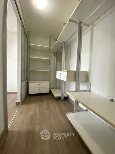 Spacious walk-in closet with modern shelving and drawers in a stylish apartment.