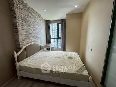 Cozy bedroom with modern brick accent wall and large window offering city views.