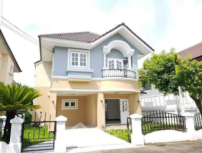 Charming two-story house with gated driveway and lush greenery