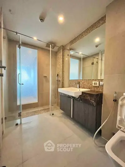 Modern bathroom with glass shower and sleek vanity in luxury apartment.