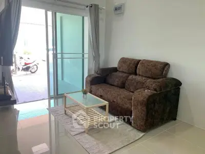 Cozy living room with plush sofa and glass coffee table, sliding doors to patio.