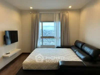Modern bedroom with city view, featuring a sleek leather sofa and wall-mounted TV.