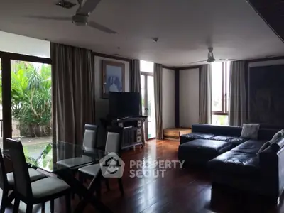 Spacious living room with modern furniture and large windows overlooking lush greenery.