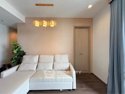 Modern living room with beige sofa, stylish lighting, and elegant curtains.