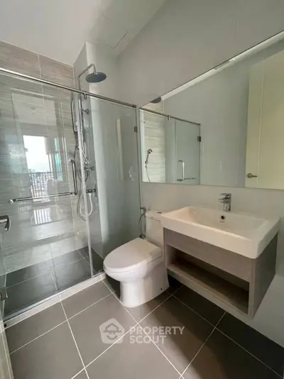 Modern bathroom with glass shower and sleek fixtures in contemporary apartment.