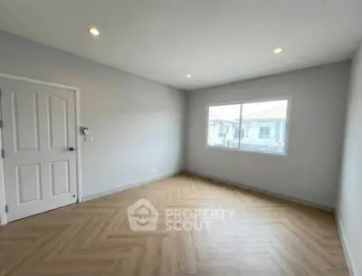 Spacious empty room with wooden flooring and large window in modern home