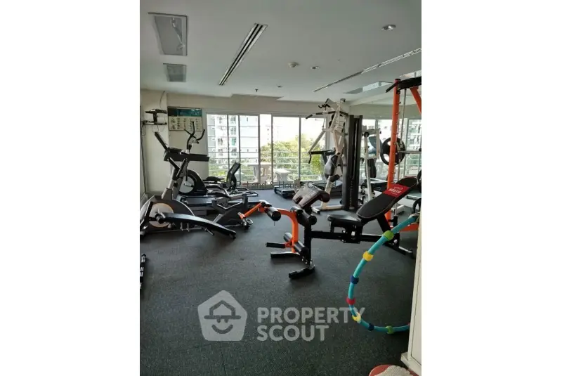 Modern gym with exercise equipment and large windows in residential building