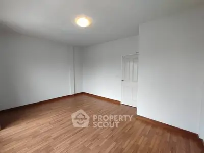 Spacious empty room with wooden flooring and white walls, ideal for customization.