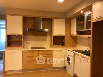 Modern kitchen with wooden cabinets, washing machine, and sleek appliances in a cozy apartment.