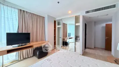 Spacious bedroom with modern furnishings and large windows for natural light.