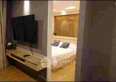Modern bedroom with wall-mounted TV and cozy lighting