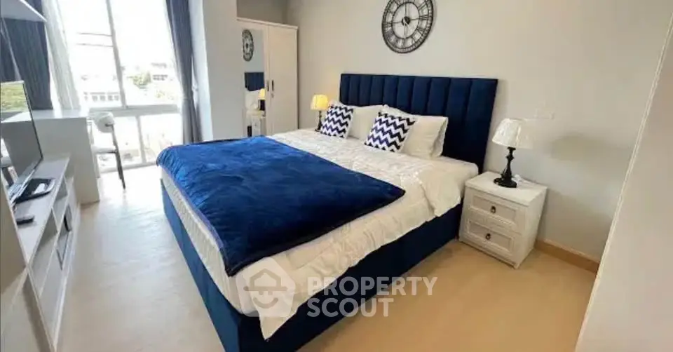 Spacious bedroom with modern decor and large window for natural light.