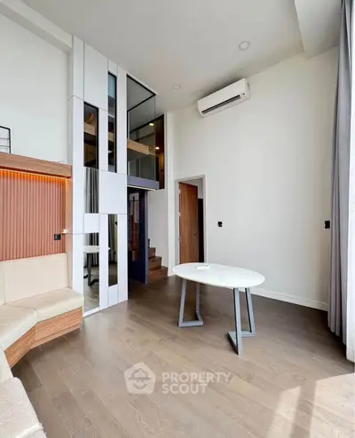 Modern living room with high ceiling, stylish furniture, and air conditioning in a contemporary apartment.