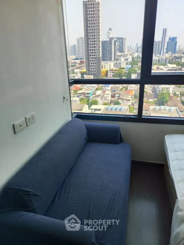Cozy corner unit with stunning city view from high-rise apartment, featuring a comfortable blue sofa.