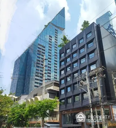 Modern high-rise glass facade building towers over the surrounding architecture, offering a blend of luxury living and innovative design in a prime urban location.