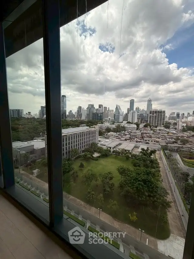 Stunning cityscape view from high-rise building window with lush greenery below.