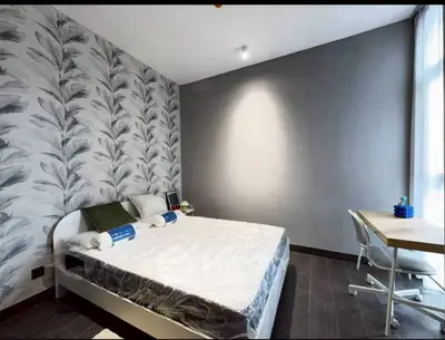 Modern bedroom with stylish wallpaper and natural light, featuring a cozy bed and a functional study desk.