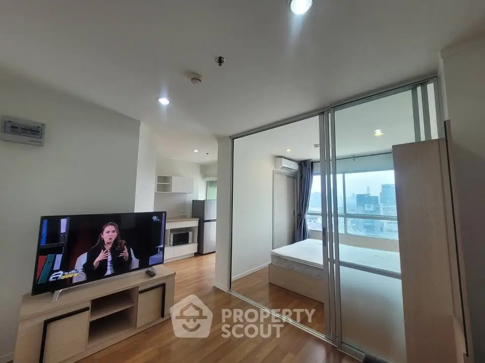 Modern studio apartment with open layout and city view, featuring sleek kitchen and cozy living area.