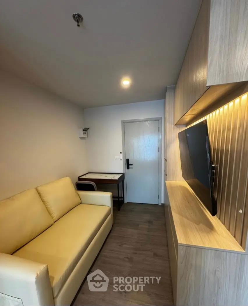Modern living room with sleek design, featuring a cozy sofa and wall-mounted TV, perfect for relaxation.